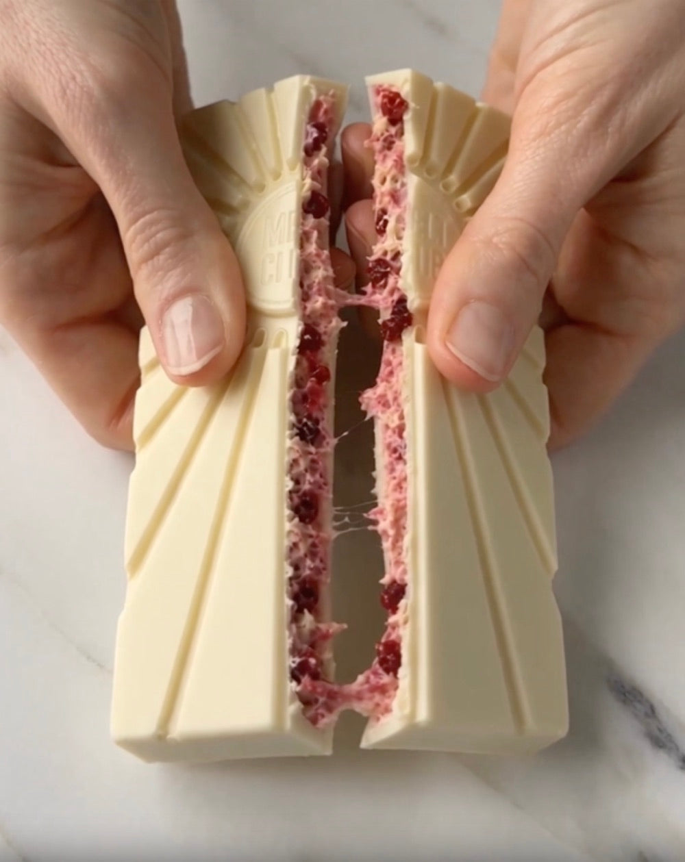 White chocolate bar split open, raspberry cheesecake center